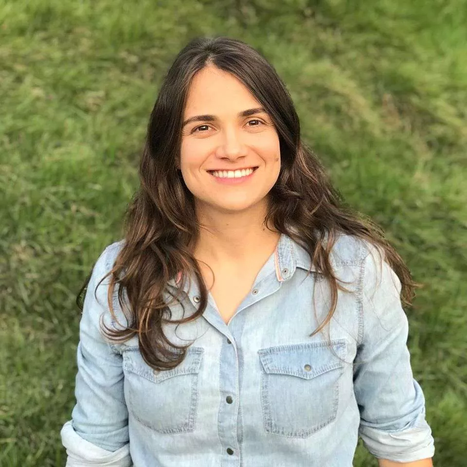 Foto de Letícia Aquino com uma camisa azul clara e um fundo de grama bem verde