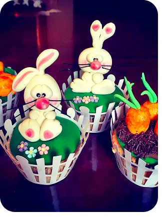 Cupcakes no tema Páscoa com cores fortes com coelhos no topo do cupcakes, e alguns com cenouras enterradas no granulado do Curso Meu Primeiro Zoológico - Modele 25 Animais em Pasta Americana