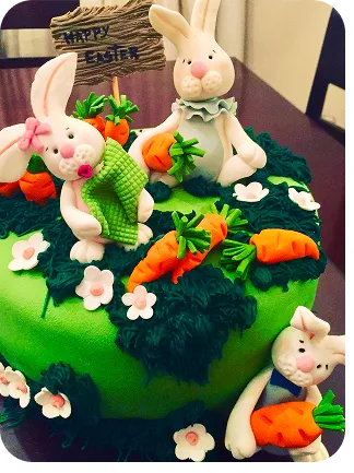 Bolo de 1 andar no tema Páscoa com família de coelhos, cenouras e um jardim com flores, na base um outro coelho e sua cenoura do Curso Meu Primeiro Zoológico - Modele 25 Animais em Pasta Americana