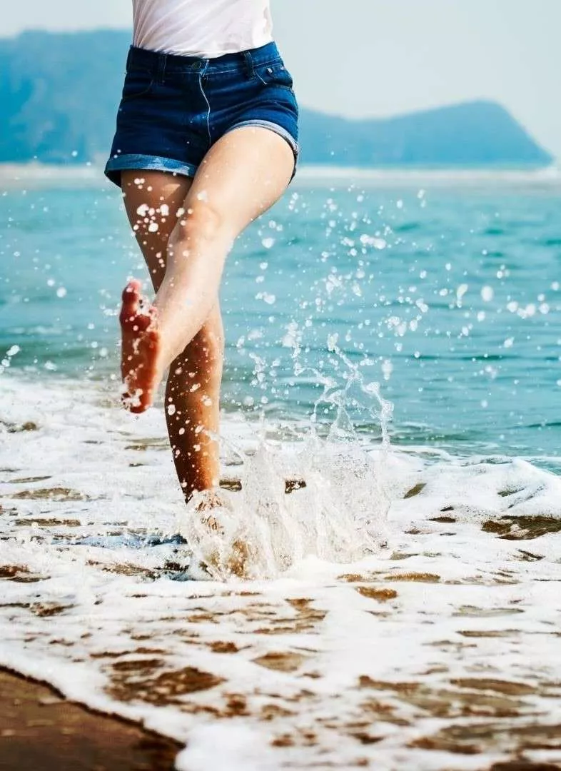 Mulher chutando a água na praia