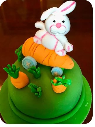 Bolo de 1 andar no tema Páscoa com cores fortes, no topo do bolo um coelho sobre um skate feito de cenoura e cenouras enterradas no bolo do Curso Meu Primeiro Zoológico - Modele 25 Animais em Pasta Americana